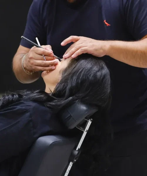 Profissional aplica maquiagem nos olhos de uma cliente na Gris Esmalteria